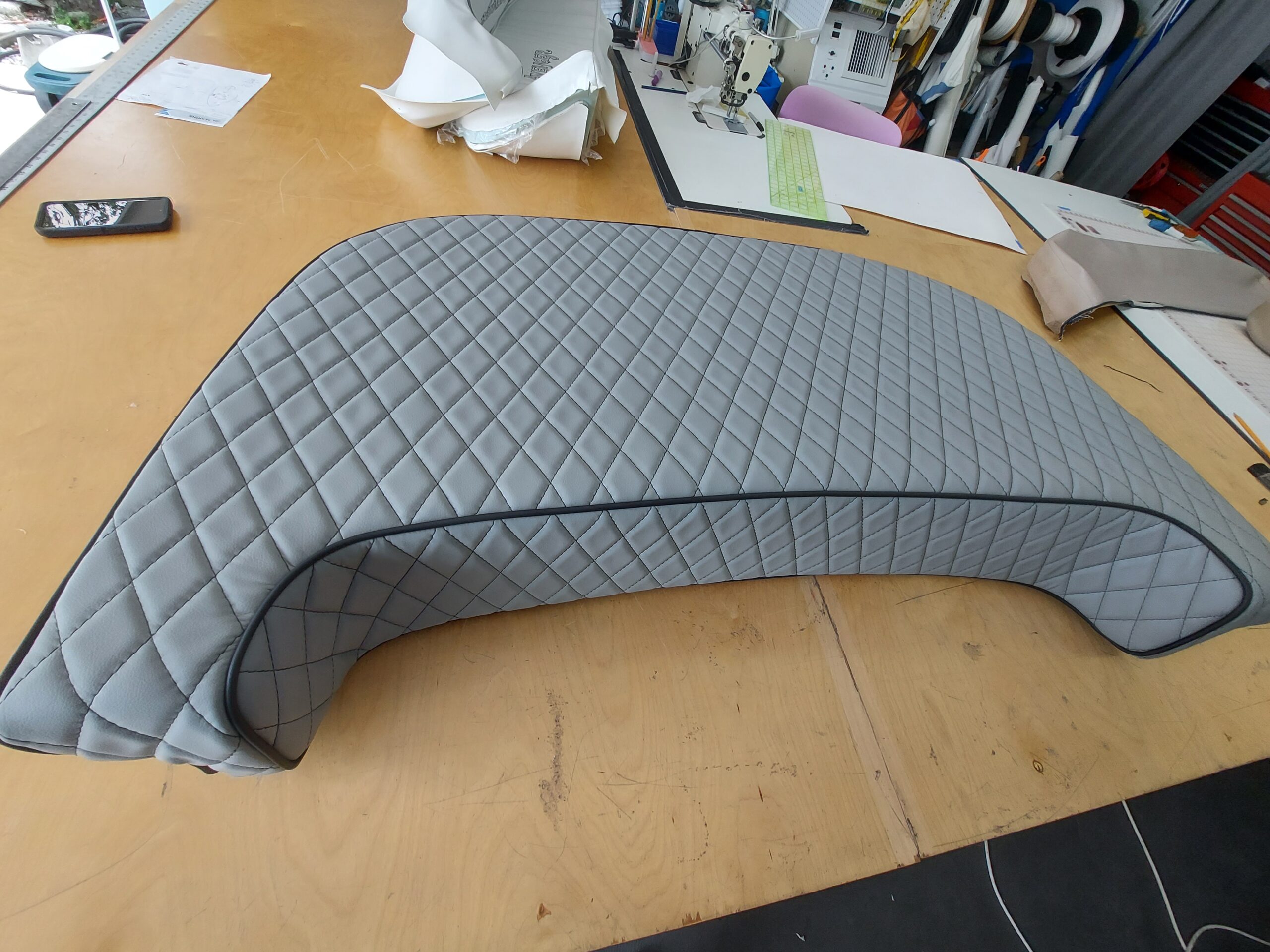 Custom gray curved marine cushion with diamond stitching and dark piping.