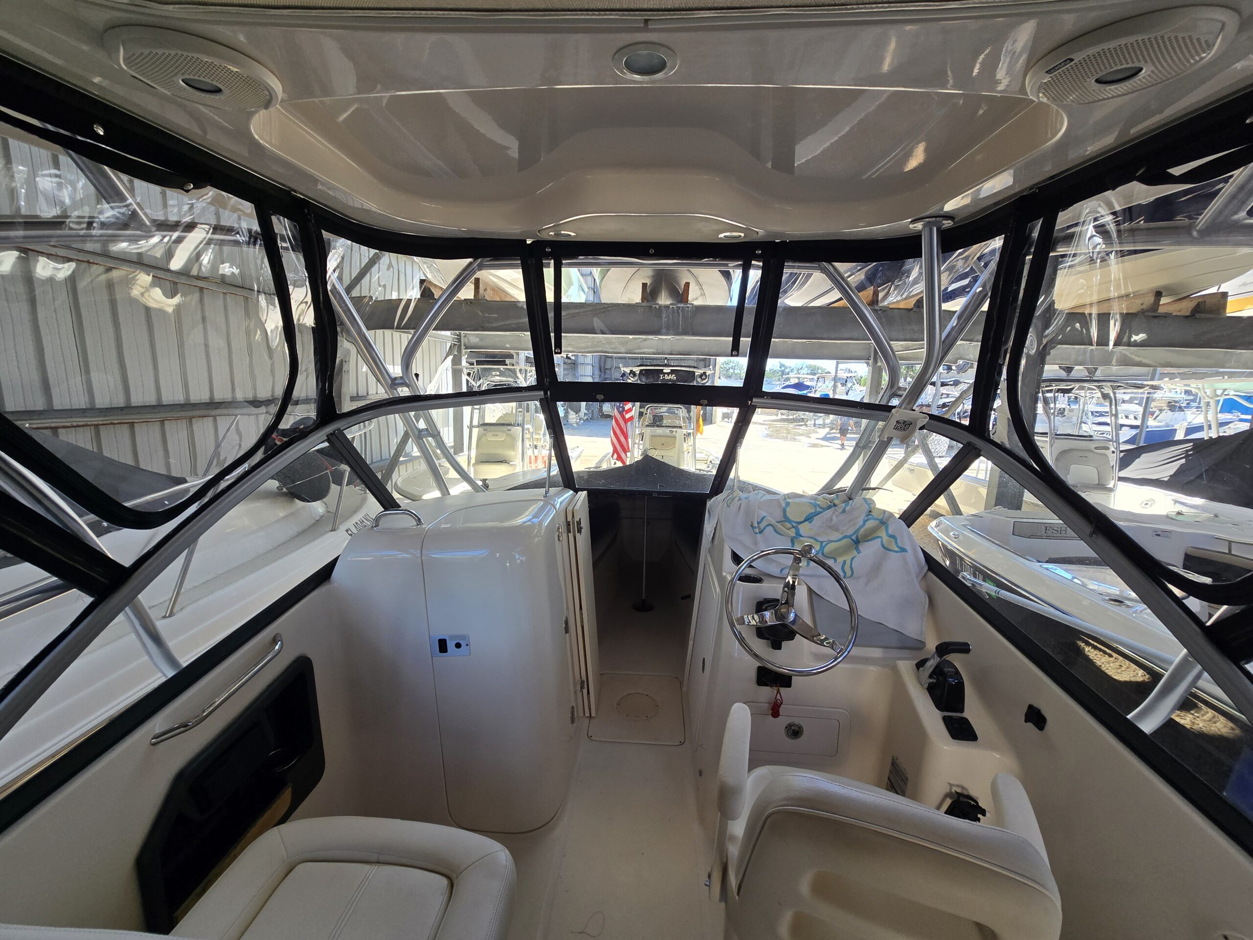 Interior view of a fitted clear vinyl boat enclosure with black canvas edging and zippered panels.
