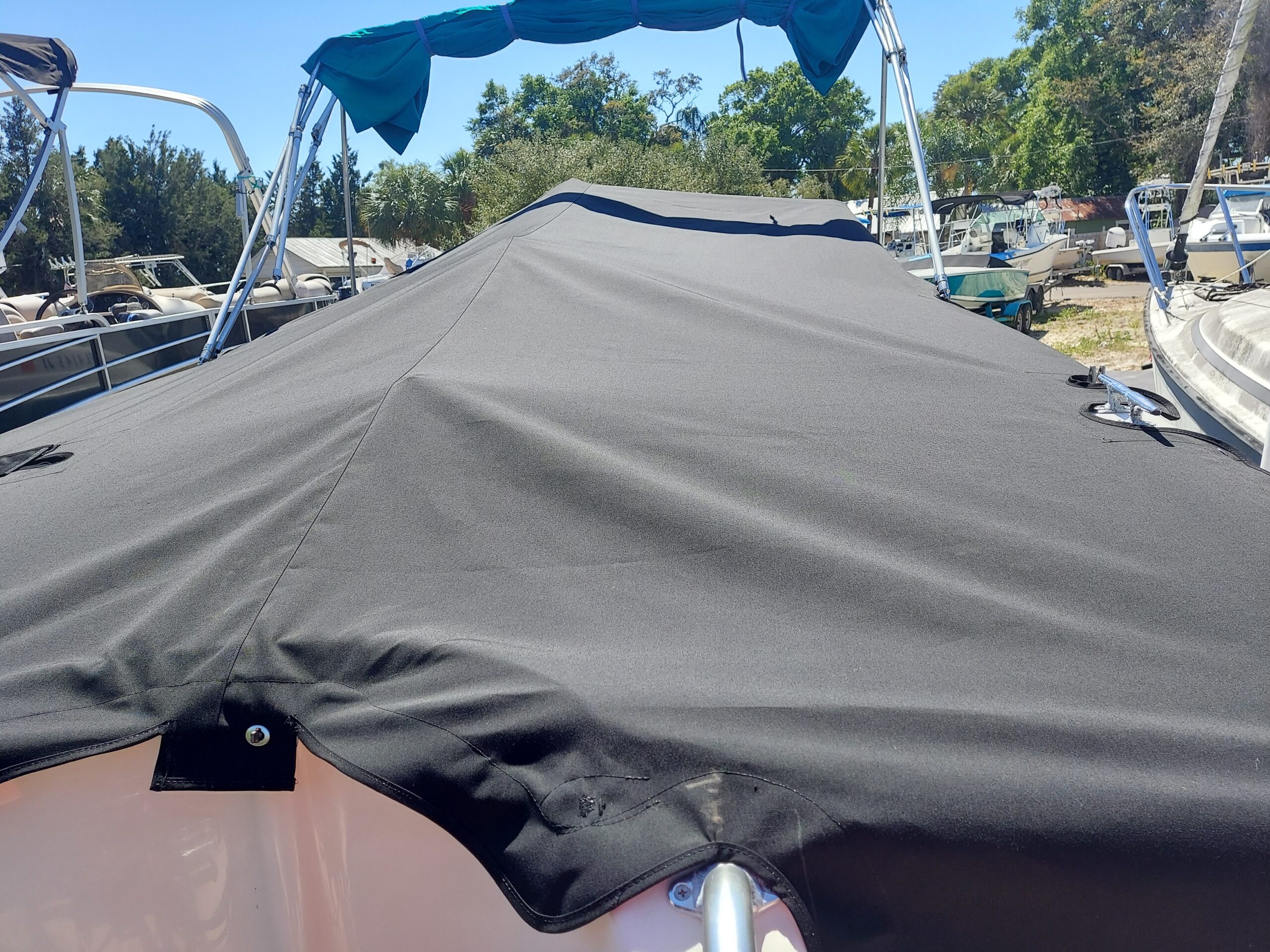 Custom gray marine canvas cockpit cover fitted beneath a boat's folded Bimini frame.